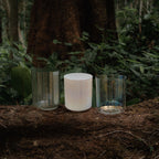 Terratone Signature 3-Bowl Set in earthy green crystal quartz tones displayed on natural moss and stone in a lush forest setting, featuring lightweight travel-ready crystal singing bowls inspired by nature and