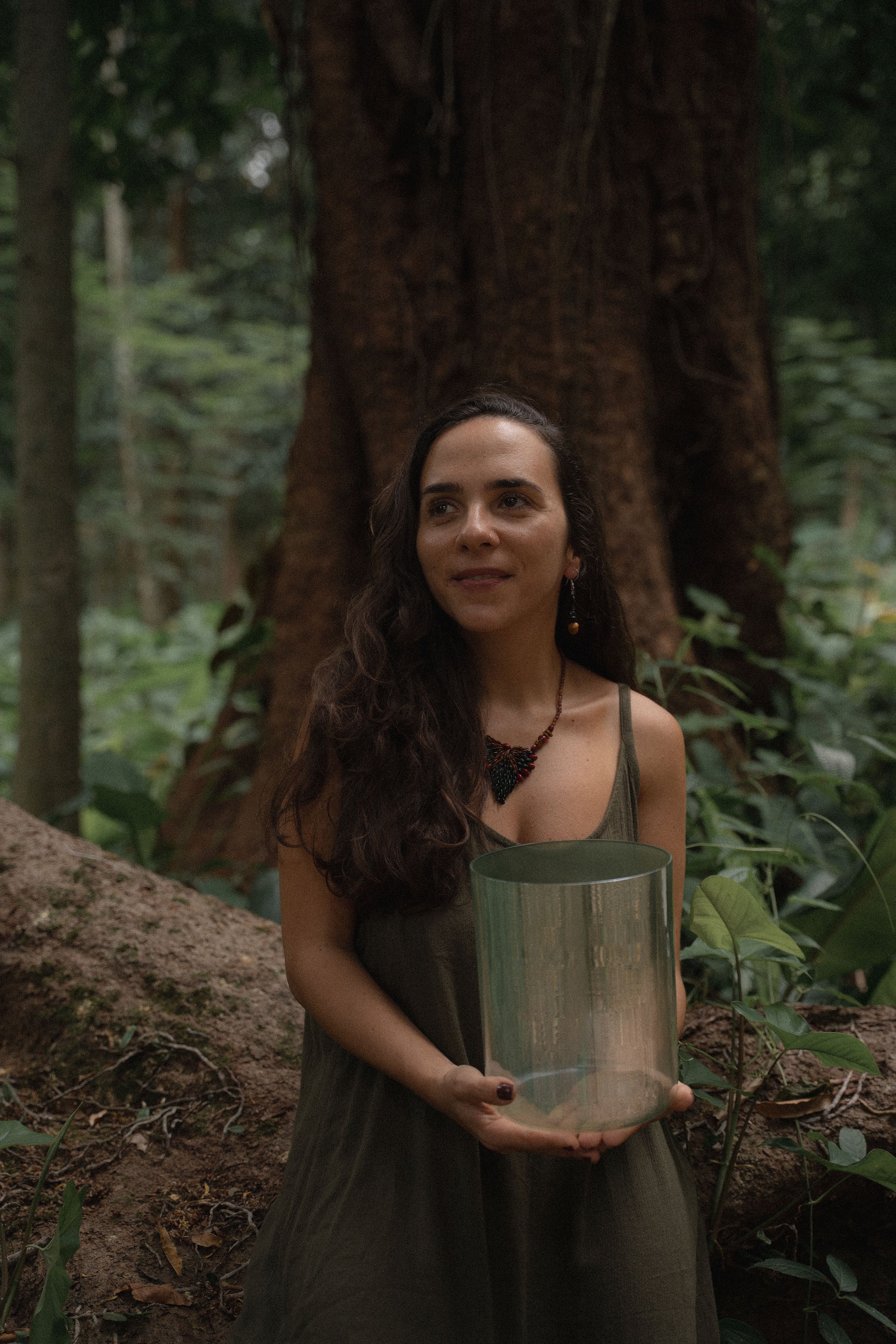 Founder of Terratone holding a crystal singing bowl in a tropical forest during a personalized bowl consultation experience.