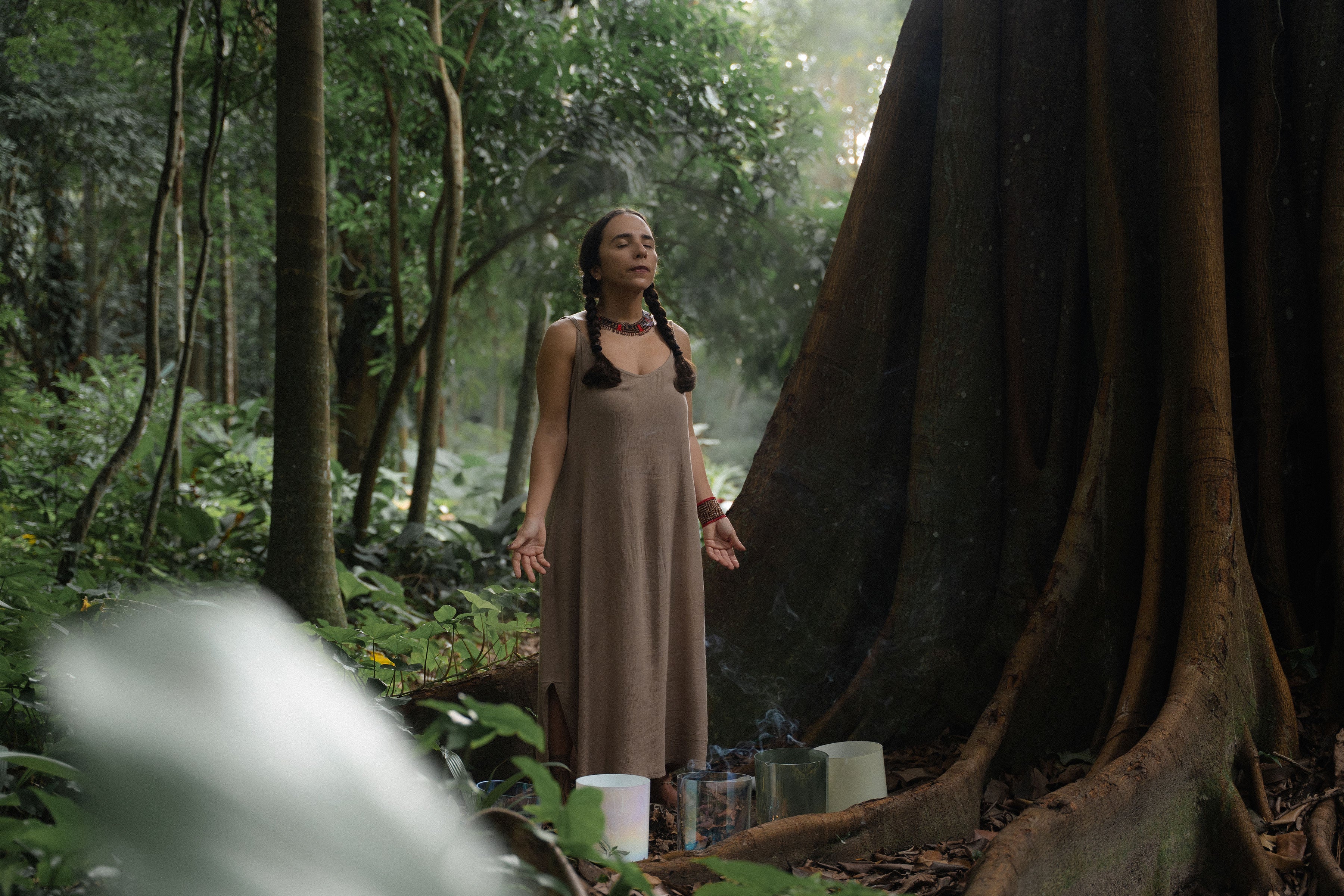 Sound healer standing in the forest surrounded by Terratone crystal singing bowls during a grounding meditation ritual.